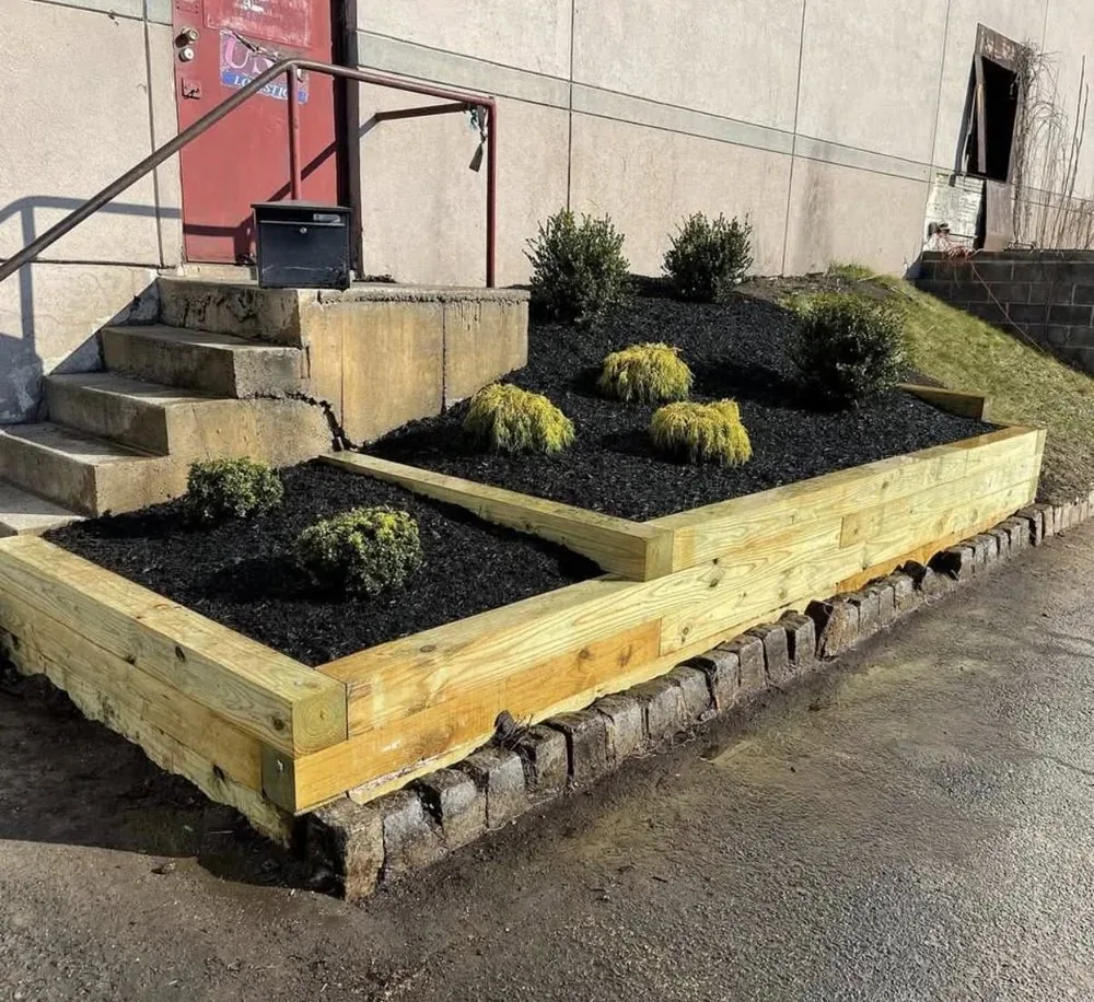 Timber retaining beds with layered shrubs at a commercial entry