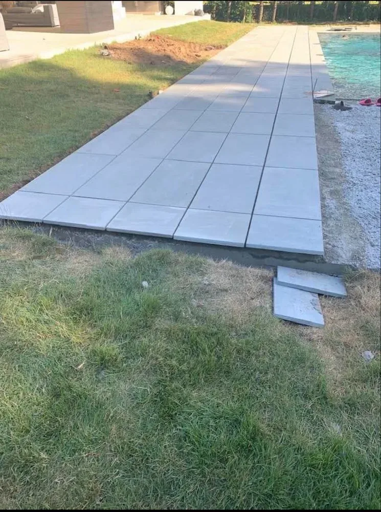 Large-format bluestone pool deck being set plank by plank
