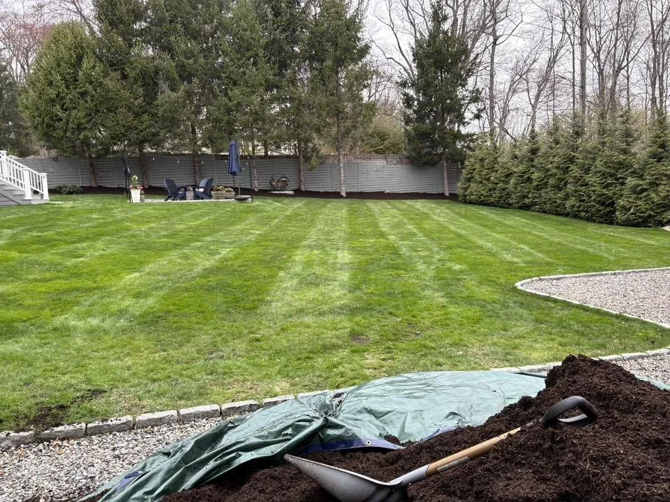 Mulch delivery and spring cleanup on a striped backyard lawn