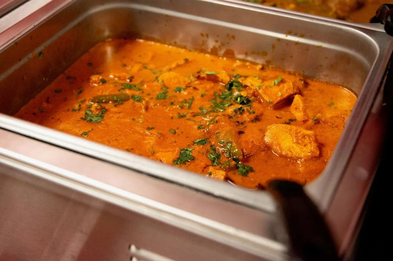 Creamy chicken curry garnished with cilantro in a buffet tray
